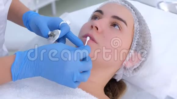 美容师在永久化妆前在女性嘴唇上涂上麻醉剂乳霜视频的预览图