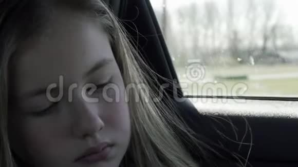 坐在汽车后座上的无聊女孩伤心的女孩望着车窗外视频的预览图