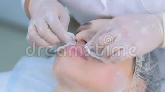 美容师在美容诊所用棉垫擦拭女性面部面膜视频的预览图