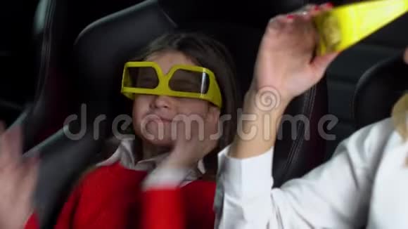 带着小女儿的女人带着3D眼镜看电影视频的预览图