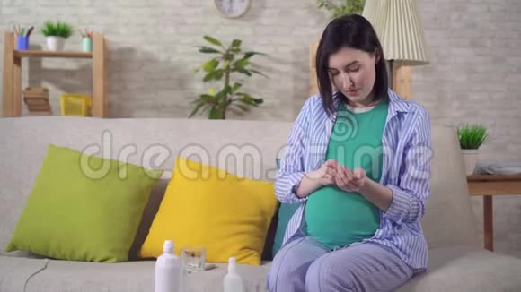 年轻的孕妇在沙发上吃药视频的预览图