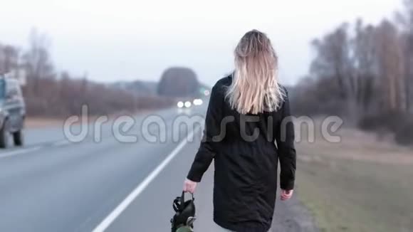 一个走在公路边上的女孩手里拿着一个黑色的防毒面具视频的预览图