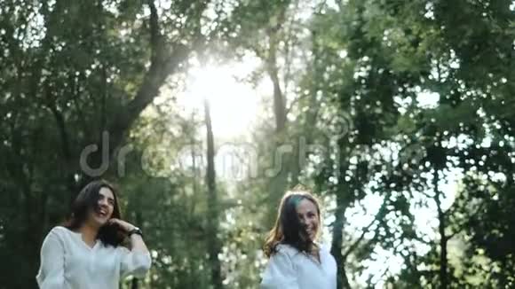 在一个温暖阳光的夏日两个迷人的女人在镜头前跳跃和微笑为两个人拍摄有趣的照片视频的预览图