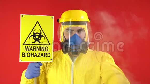 一个男人戴着防护化学面具穿着黄色防护服手里拿着一个横幅上面写着生物危险视频的预览图