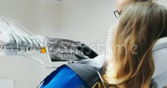 牙医用X光向年轻女子展示她的牙齿视频的预览图