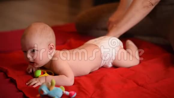 孩子在家里的地毯上被一个骨伤者按摩婴儿骨盆和腿是用按摩或手工操作的视频的预览图