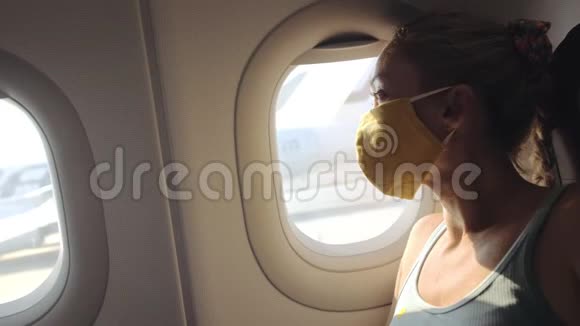 女人在飞机上旅行白种人戴着防护医疗面罩防护呼吸器飞机女游客视频的预览图