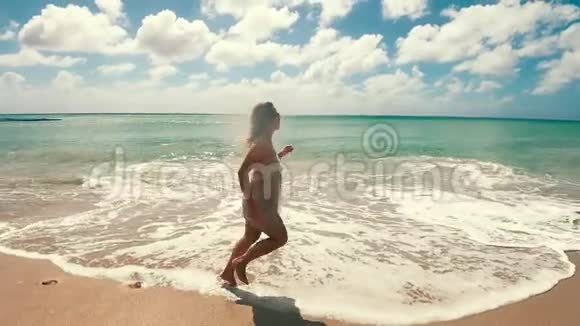 美丽的女人正慢慢地沿着海滩奔跑视频的预览图