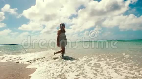 阳光明媚的海滨和一个快乐的女人沿着它走视频的预览图