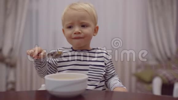 快乐的婴儿用勺子吃食物笑开心萌娃在厨房吃水果捣碎可爱的孩子视频的预览图