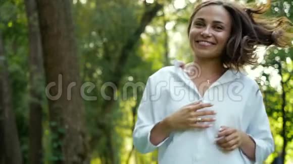 一个美丽的微笑的女人绿眼睛蹦蹦跳跳摆出一张好的纪念品照片在一个城市的秋天公园里视频的预览图