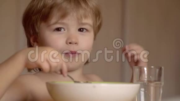 小男孩坐在桌子旁吃牛奶零食婴儿用勺子吃食物可爱的小画像视频的预览图