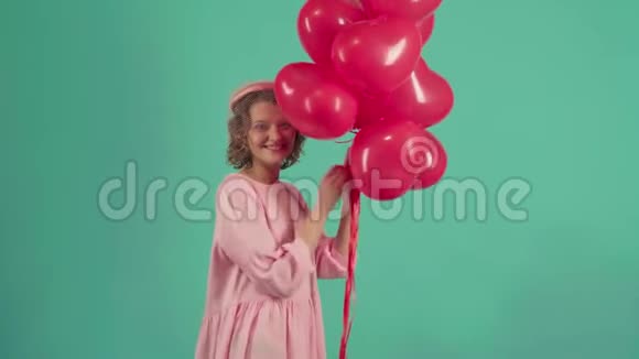 情人节女孩带着红色气球笑绿色背景庆祝情人节快乐年轻女子视频的预览图