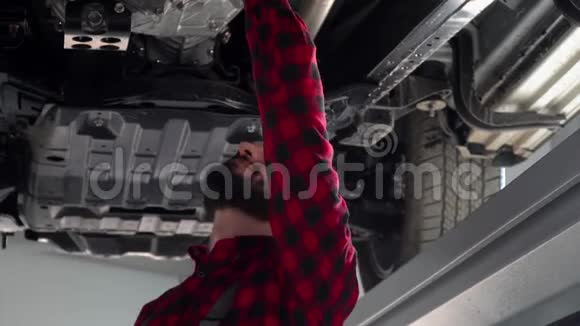 大胡子修理工在汽车修理厂修理一辆汽车汽车服务维修和保养视频的预览图