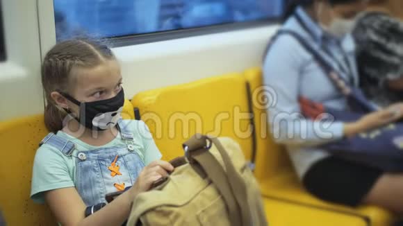 小女孩旅行白种人乘坐在地面列车上戴着防护医疗红色面具儿童婴儿视频的预览图