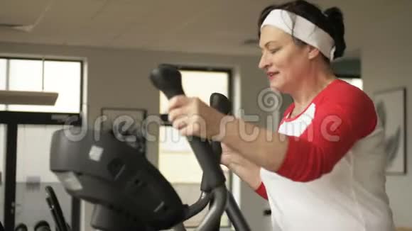 有魅力的白种人老女人在训练机上工作在健身中心看起来很开心健身和活跃视频的预览图
