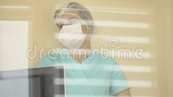 护士或医生戴着医用口罩和一次性帽子看着监视器屏幕视频的预览图