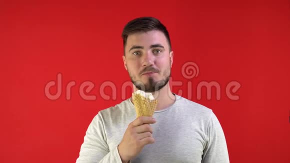 迷人的男人在红色背景下吃冰淇淋隔离带视频的预览图