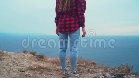 穿着黑色和红色衬衫的长发性感女孩站在大海的背景下女孩举起双手视频的预览图