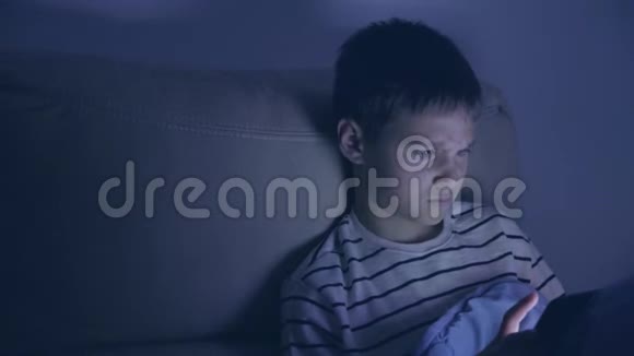 青少年男孩晚上在家使用平板电脑小男孩玩电脑游戏看视频上网冲浪视频的预览图