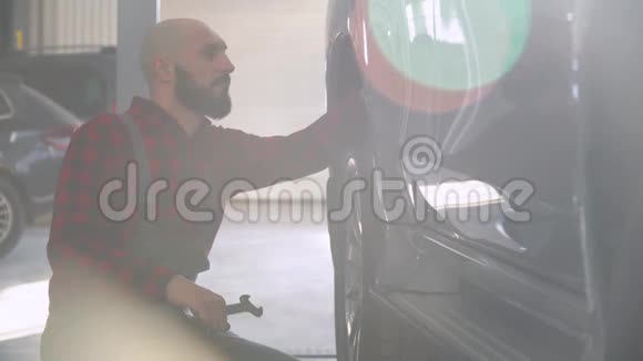 大胡子修理工在汽车修理厂修理一辆汽车汽车服务维修和保养视频的预览图