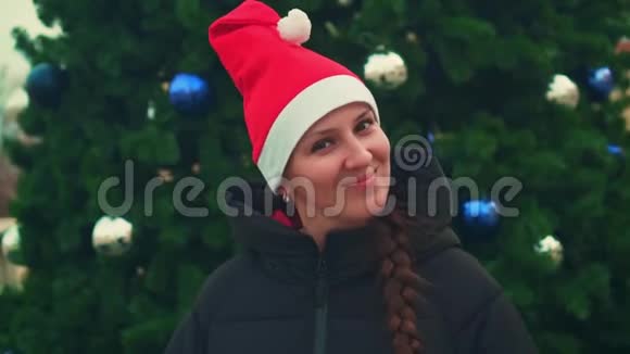 戴圣诞帽的年轻女子在圣诞树背景上庆祝圣诞节或新年视频的预览图