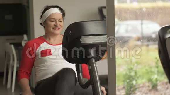 中年妇女在健身房或健身中心用文具自行车做有氧运动视频的预览图