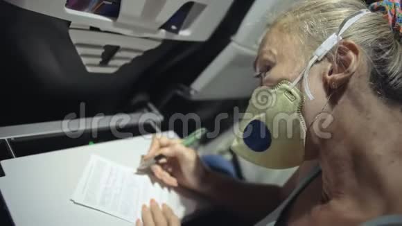 女人在飞机上旅行白种人戴着防护医疗面罩防护呼吸器飞机女游客视频的预览图