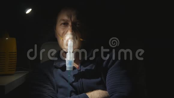 一个男人晚上在一个有小灯泡的房间里用喷雾器吸入他专注地盯着相机关门视频的预览图