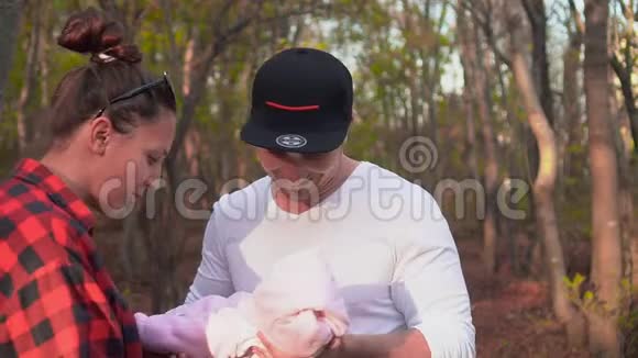 快乐的年轻父母和女儿一个年轻人把一个小女孩抱在怀里递给她妈妈视频的预览图