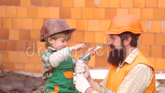 小儿子工人竖起砖墙男孩扮演建筑工或修理工儿子帮手孩子对未来职业的梦想视频的预览图