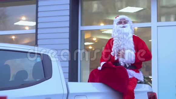 圣诞老人坐在一辆皮卡的后面在汽车经销商的圣诞老人视频的预览图