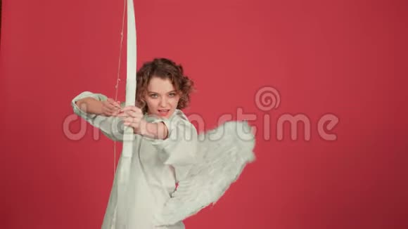 情人节的人的概念天使女孩带着弓箭越过红色背景爱的概念有趣的天使女人视频的预览图