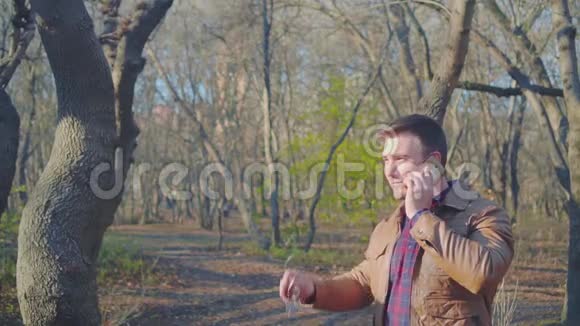 穿着皮夹克棒球帽和时髦太阳镜在智能手机上说话的人的肖像微笑的家伙视频的预览图