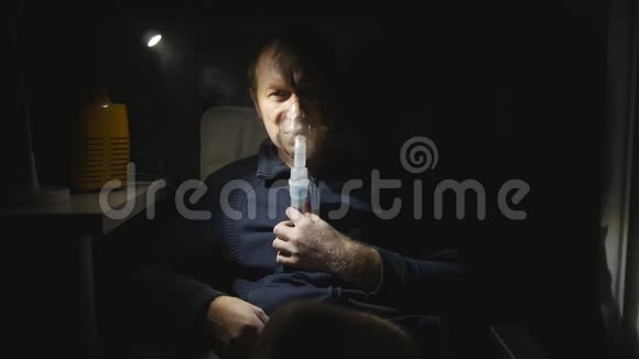 一名中年男子在夜间通过雾化器呼吸治疗支气管炎的药物他病了夜灯发出的光视频的预览图