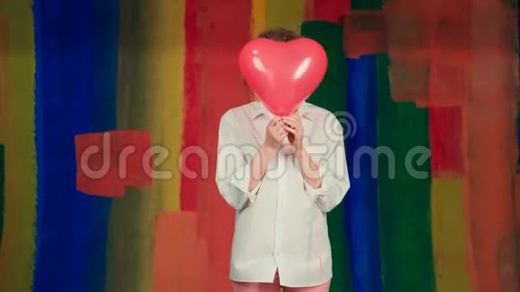 有趣的女孩带着红色的心脏气球美女带着五颜六色的气球笑在彩虹的背景上视频的预览图