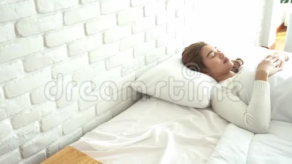 女人在床上醒来后伸展手臂视频的预览图