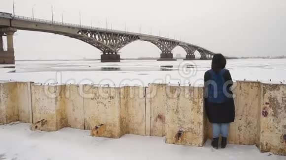 冬天一个女孩在河边的街道上拍照女摄影师在城市的桥边拍照视频的预览图