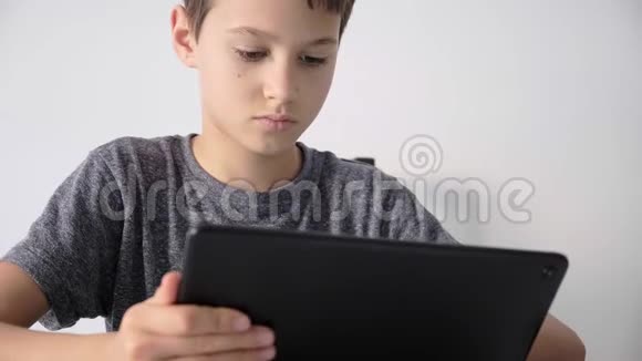 专注的孩子使用数字平板技术设备男孩手持电脑观看视频在线学习视频的预览图
