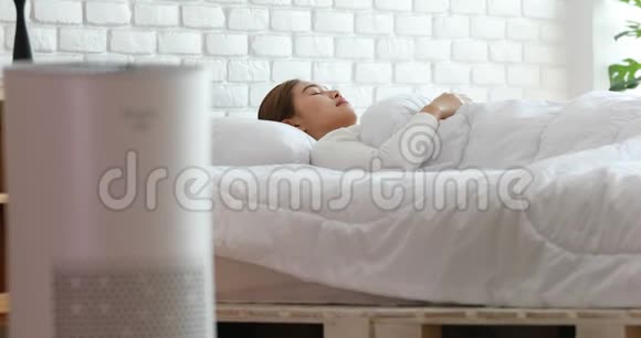 在舒适的白色卧室里女人与空气净化器一起睡觉用于过滤和清洁去除灰尘PM25HEPA视频的预览图