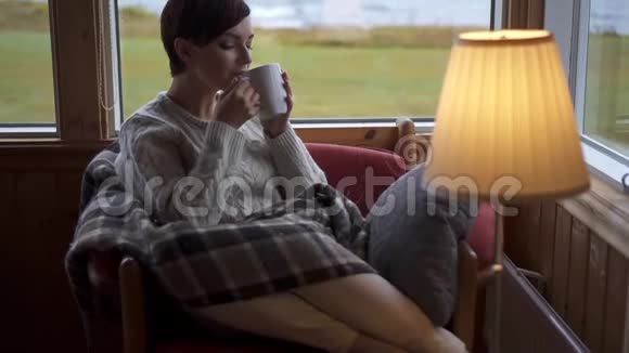 一个女人在家里的扶手椅上喝茶视频的预览图