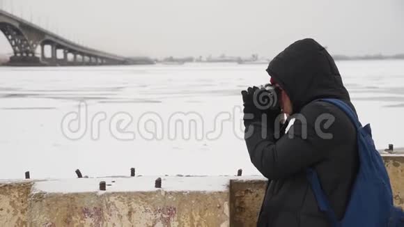 女游客在河边拍摄一幅冬季景观女摄影师为街上的桥拍照视频的预览图