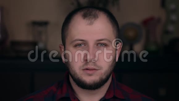 一个年轻的欧洲人穿着格子衬衫坐在椅子上滚动着他的眼睛头晕目眩视频的预览图