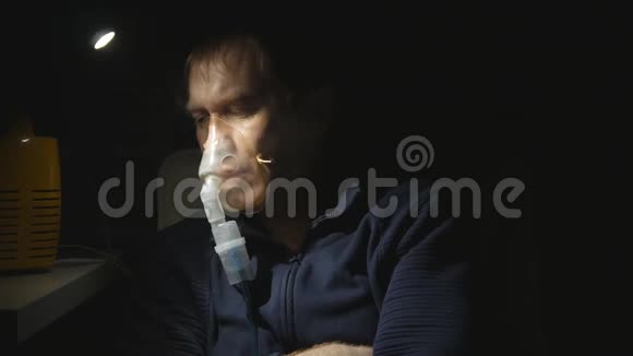 一个年轻英俊的男人用喷雾器吸入他咳嗽结束了会议摘下面具从椅子上站起来视频的预览图