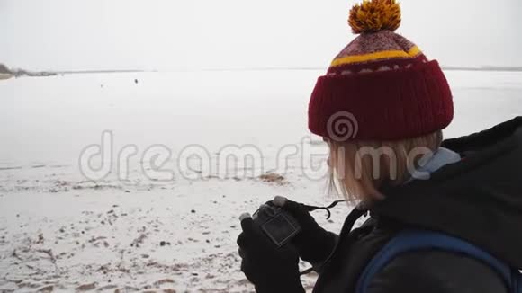 一个女孩在桥附近拍摄一条冰冻的河流冬天女摄影师在大自然中拍照视频的预览图