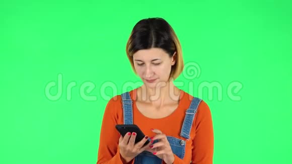 年轻微笑的女人在手机上发短信绿色屏幕视频的预览图
