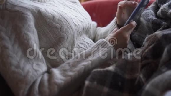 一个女人在家里的沙发上使用智能手机视频的预览图