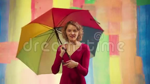 开朗的白种人年轻女子带着彩虹伞在彩色演播室的背景下玩得很开心有趣的感情女孩视频的预览图