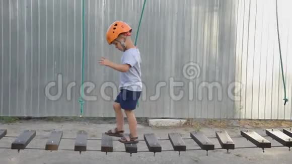 婴儿正在街上的一个绳镇玩耍一个男孩走在孩子们设备上一个孩子坐在摇摇晃晃的木桥上视频的预览图