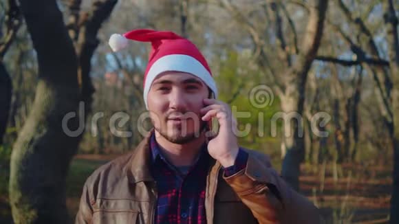 一个戴着圣诞帽的男人在电话里祝他的亲戚和朋友圣诞快乐视频的预览图